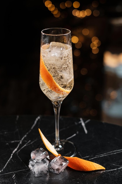 Sparkling wine in a glass with ice and orange zest