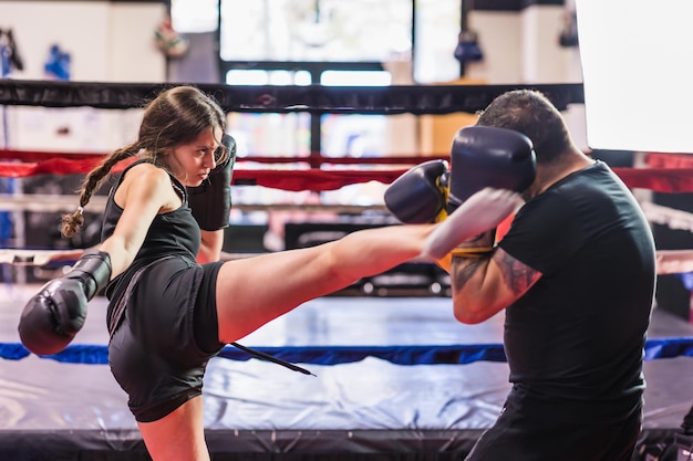 Sparring selfdefense k kickboxing hispanic young sportswoman with mature fitness trainer in gym