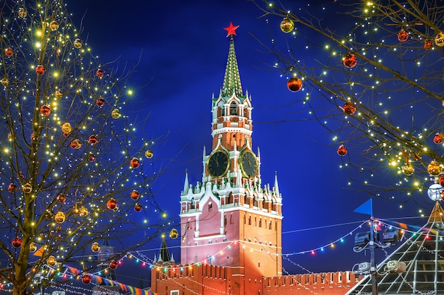 Spasskaya Tower on Red Square in Moscow among New Year's trees decorated with balls on a winter night