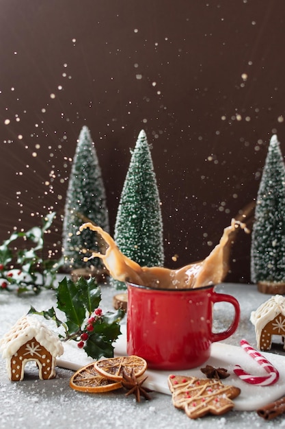 Spatten van kerstcappuccino in rode mok op grijze tafel met peperkoekkoekjes.