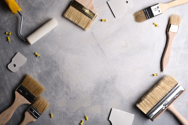 Foto spatole per l'applicazione di stucco e pennelli e rulli per la pittura su uno sfondo di cemento grigio. vista dall'alto