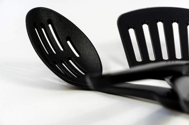 Spatulas and spoons black plastic on white background mexico