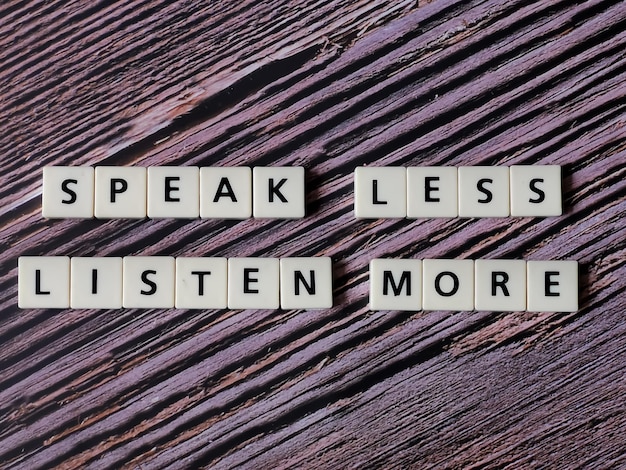 Speak less listen more word made from square letter tiles on wooden background.