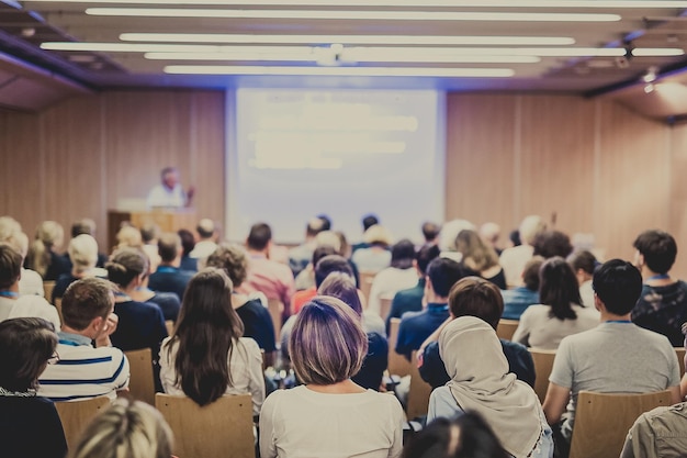 Relatore che tiene un discorso alla riunione d'affari pubblico nella sala conferenze affari e imprenditoria focus su persone irriconoscibili dal retro