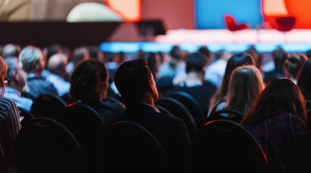 Speaker on the stage with Rear view of Audience in the conference hall or seminar meeting, business and education concept