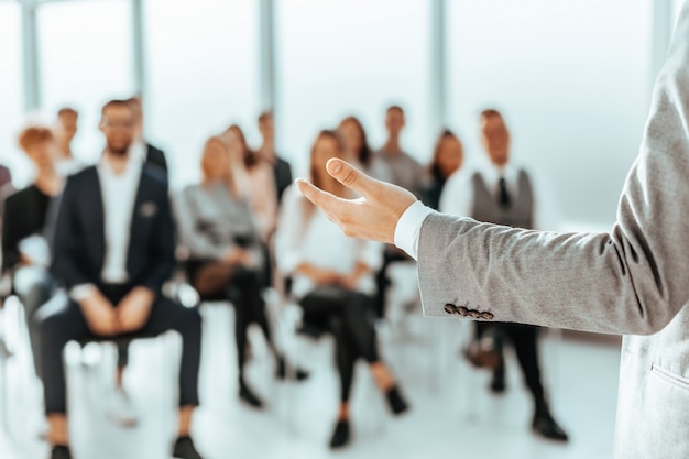 A speaker standing in front of listeners in a conference room