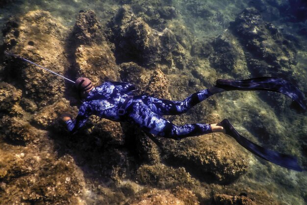 Spearfisher Swims on the Rocky Seabed