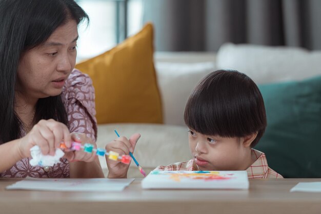 엄마 와 함께 집 의 거실 에서 그림 을 그리고 색채 를 칠 하는 특별 한 아이