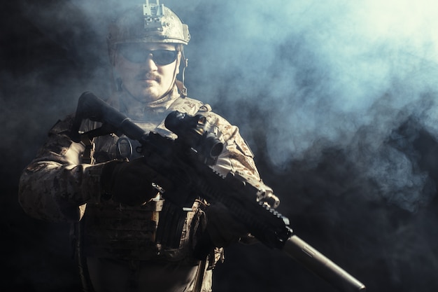 Special forces soldier with rifle on dark surface