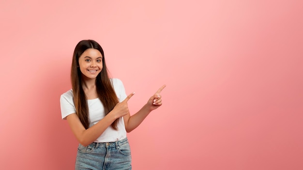 Special offer cheerful teen girl pointing at copy space with two fingers
