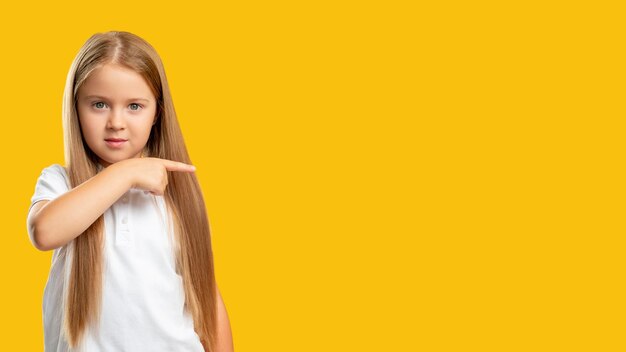 Special offer Commercial background Sale discount Confident little girl showing presenting pointing finger at invisible product information text isolated on yellow copy space
