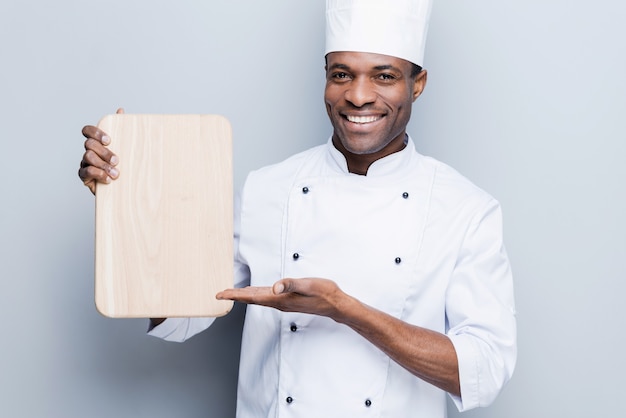 Special offer from chef. Confident young African chef in white uniform 