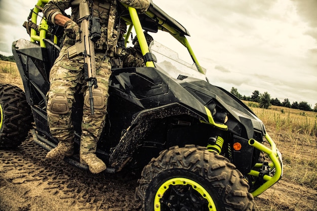 Special operations forces soldiers, modern infantries in ocp camouflage uniform, armed assault service rifle inspecting territory on desert patrol vehicle, moving on battlefield at off road carrier