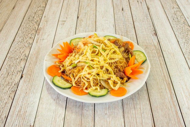 Special rice noodles with vegetables and meat sauteed in the wok on a white plate