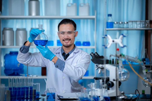 The special young male scientis or reseacher looking the chemical solution through the test tube for vaccine experiment developing at the modern biological laboratory