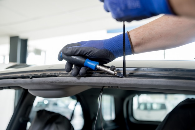 Speciale auto-arbeiders verwijderen oude voorruit of voorruit van een auto in de garage van het autobenzinestation.