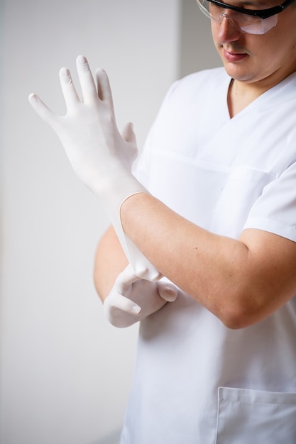 The specialist doctor puts rubber gloves on his hands before the procedure. Latex gloves to protect against germs