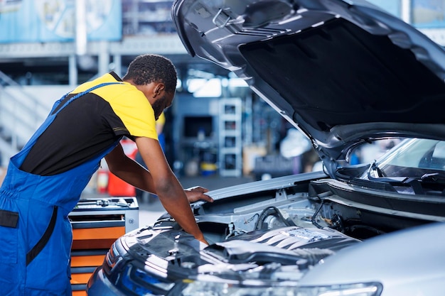 Specialist fixes car motor in garage