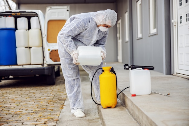 Specialist in hazmat-pakken die zich voorbereiden op het reinigen en desinfecteren van coronavirus-cellenepidemie