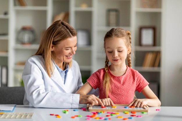 Specialist in kinderontwikkeling die met een schattig klein meisje werkt tijdens de les op kantoor