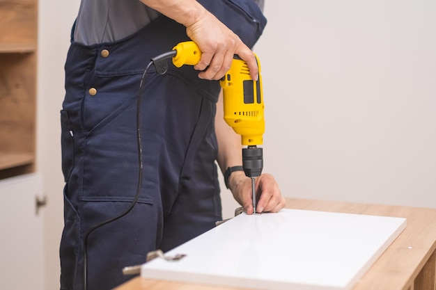 Specialist in meubelmontage met behulp van elektrische schroevendraaier boorgereedschap om houten deurrek te bevestigen