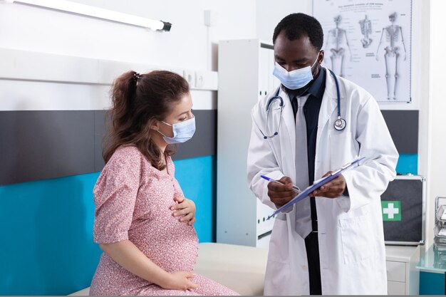 Specialist showing checkup documents to pregnant patient