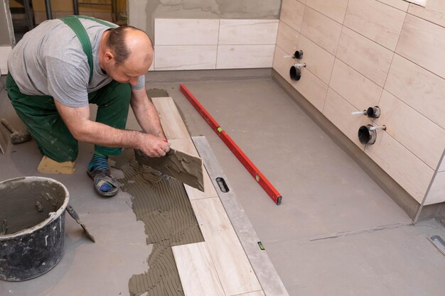 Foto un operaio edile specializzato incolla una piastrella di ceramica nella stanza del bagno