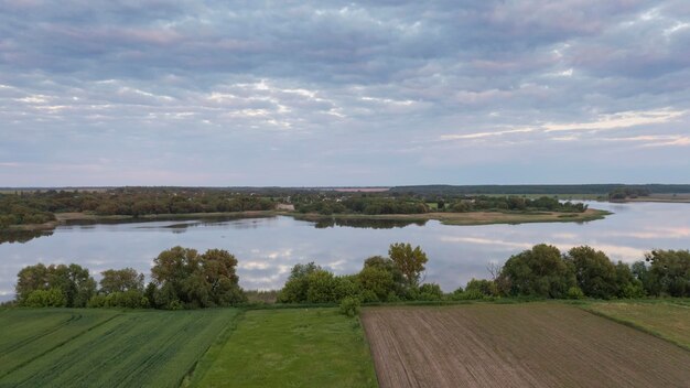 Specific landscape of a suburban landscape in the summer\
spacious agricultural land by the lake