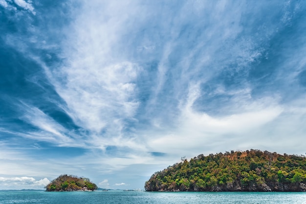 Эффектное облачное голубое небо над спокойным океаном и известняковыми скалами таиланда идеальный фон для