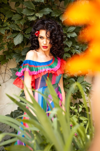 Spectacular sensual beautiful European woman with curled dark hair in a summer dress in the city