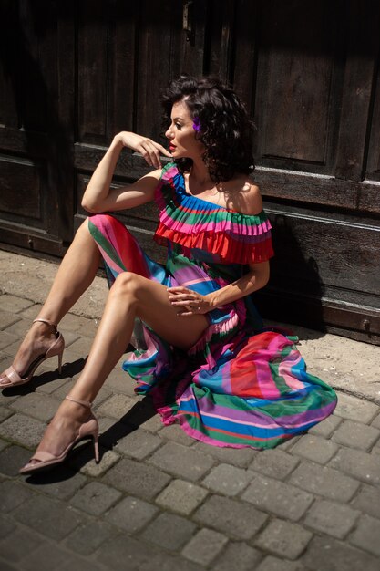 Spectacular sensual beautiful European woman with curled dark hair in a summer dress in the city