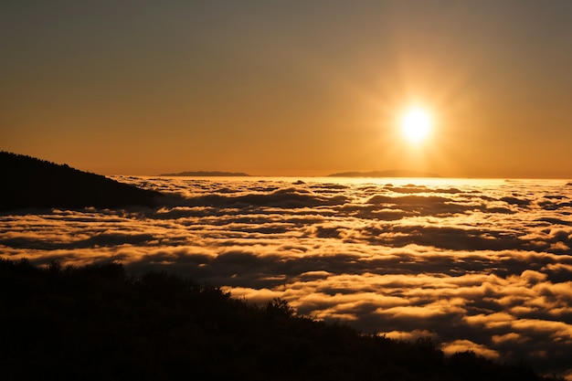 テネリフェ島のテイデ火山の国立公園の雲の上の壮大な夕日。カナリア諸島の素晴らしい夕日。