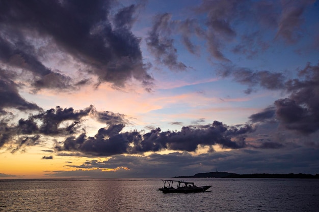 Spectacular sunset at Gili Air island with colorful sky and boat in the sea, Bali, Indonesia