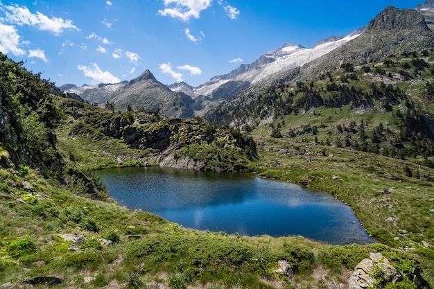 HDR 색상의 베나스크(Benasque)의 산과 눈 덮인 봉우리로 둘러싸인 피레네 산맥(Pyrenees)의 호수의 장엄하고 연상시키는 풍경