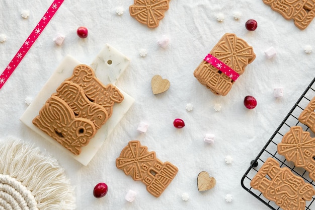 Speculoos of spekulatius kerstkoekjes chocoladeballen en lint op gebroken wit textiel tafelkleed traditionele duitse koekjes voor xmas advent wintersnacks platliggend bovenaanzicht