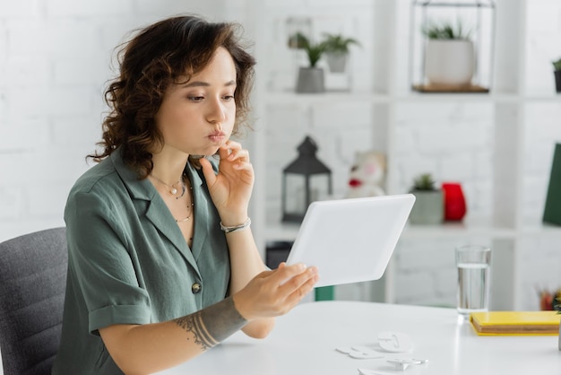 speech therapist pouting cheeks during online lesson on digital tablet in consulting room