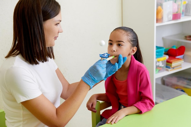 Speech therapist working with girl training pronunciation