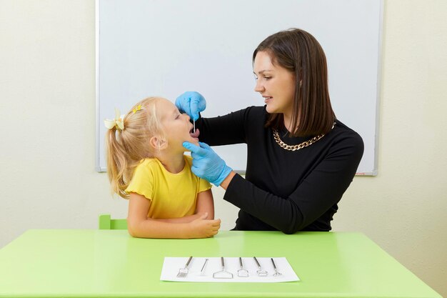 オフィストレーニングの発音で小さな女の子と一緒に働く言語聴覚士