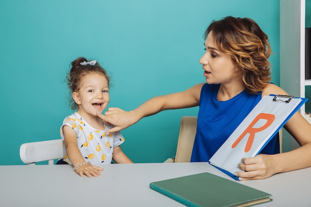 Speech therapy concept. Kid with therapist learning letters together.