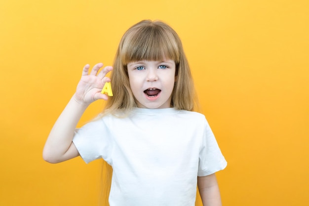 Speech therapy Toddler girl holding the letter A in her hands Classes with a speech therapist Girl on isolated yellow background