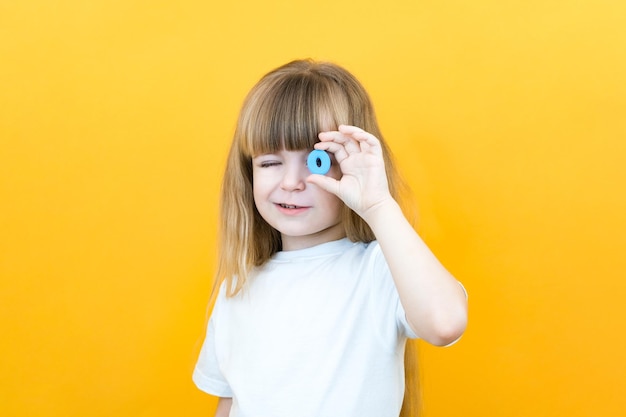 言語聴覚士の文字Oを手に持った幼児の女の子孤立した黄色の背景に言語聴覚士の女の子とのクラス