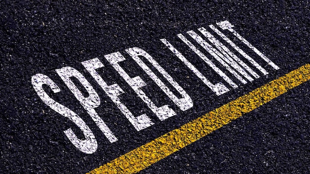 Speed Limit written and yellow line on the road in middle of the asphalt road Speed Limit word on street