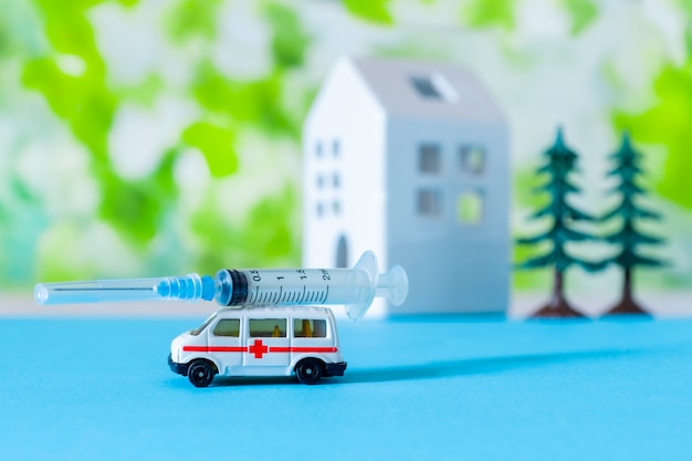 Speelgoed ambulance auto spuit blauw groen ziekenhuis teken achtergrond huis covid 19 boom