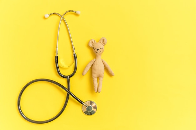 Speelgoed beer en geneeskunde apparatuur stethoscoop geïsoleerd op gele tafel
