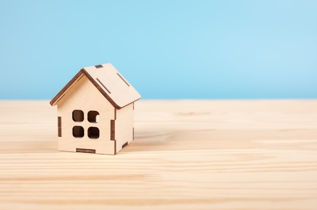 Speelgoed huis op houten tafel op blauwe baclground. huis, verzekering en hypotheek, aankoop en huurconcept.