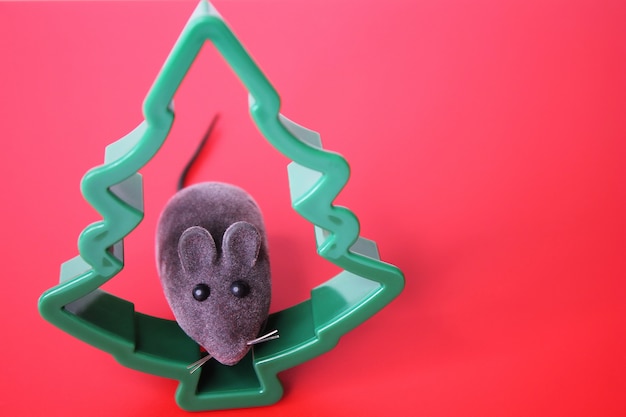 Speelgoed muis en een kerstboom op een rode achtergrond