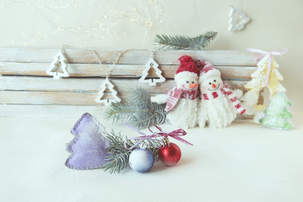 Speelgoed sneeuwmannen kerstversiering vuren takken verlichting en sneeuw op een houten achtergrond