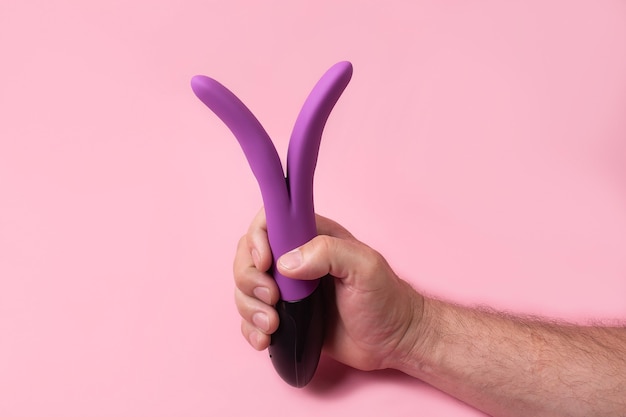 Speelgoed voor volwassenen Dildo in de hand op een roze muur