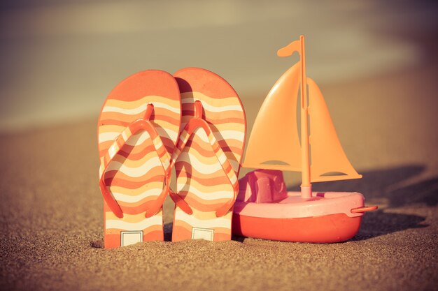 Speelgoedboot en slippers op het strand