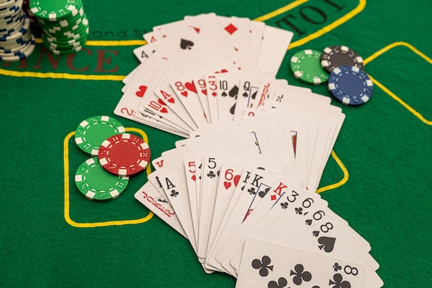 Speelkaarten van verschillende kleuren gekleurde chips verspreid over de nieuwe pokertafel